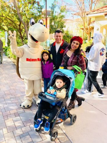 Two parents and two kids standing with Mojave Max mascot outside.